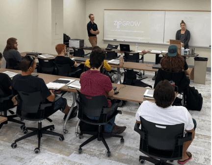 A group of people sitting in front of a whiteboard.